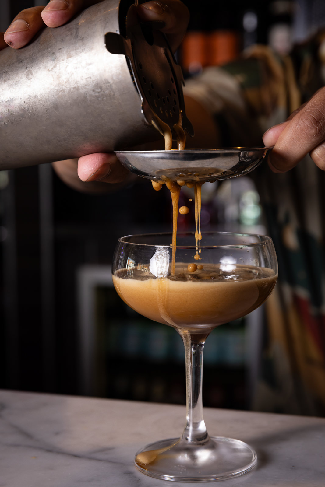 Pouring espresso martini from shaker into glass