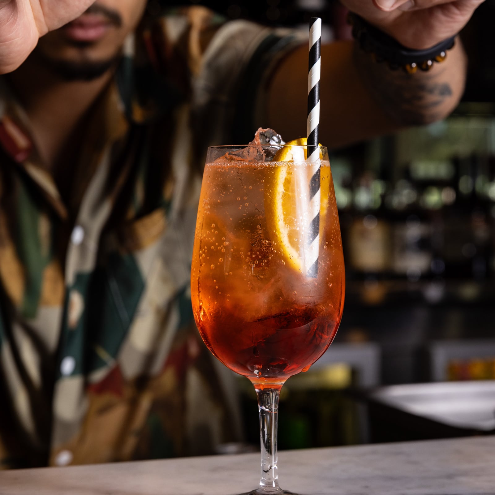 Bartender preparing orange cocktail with straw